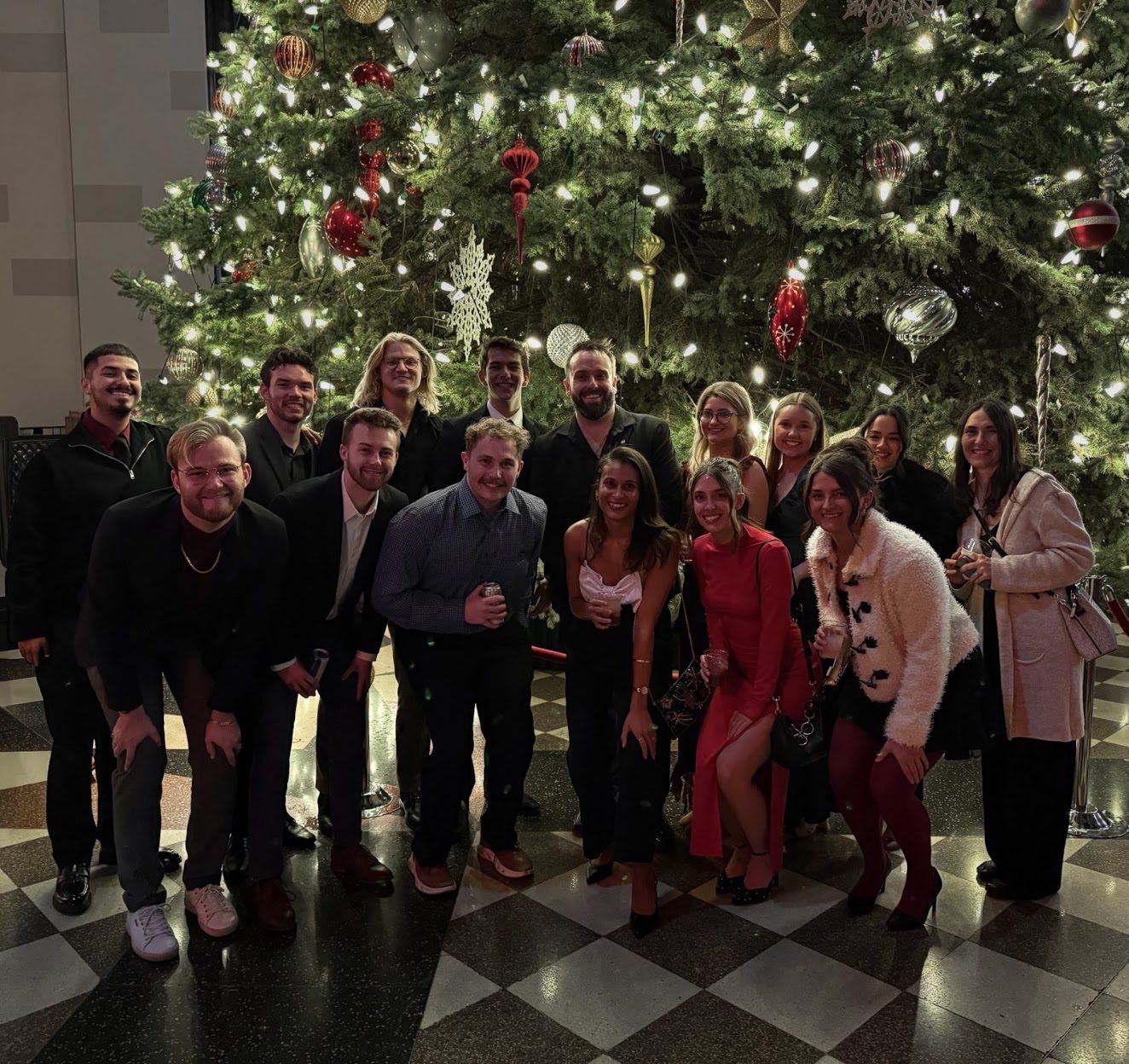Team holiday party in front of a Christmas tree